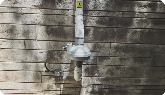 Exterior radon mitigation fan on stone wall