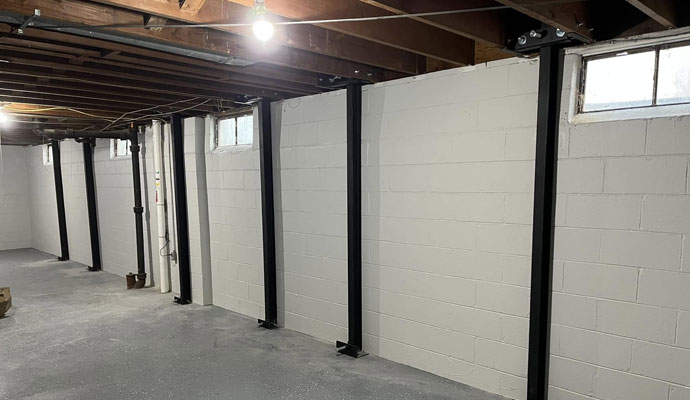 Vertical black steel beams reinforcing basement foundation wall