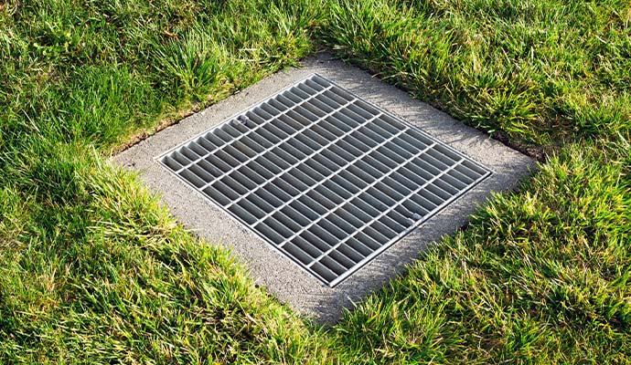 Metal storm drain grate set in concrete